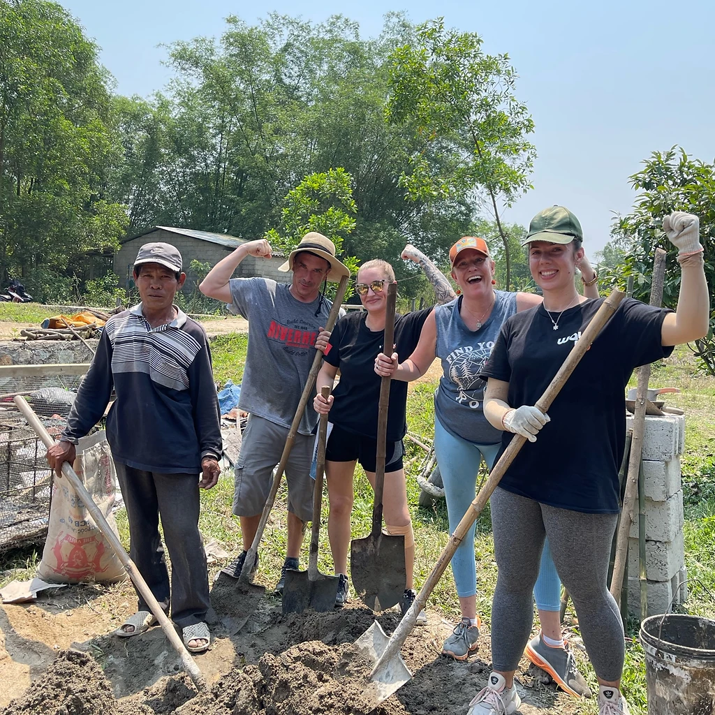 Team posing with shovels on the dirt lot