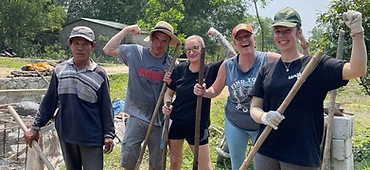 Team posing with shovels on the dirt lot