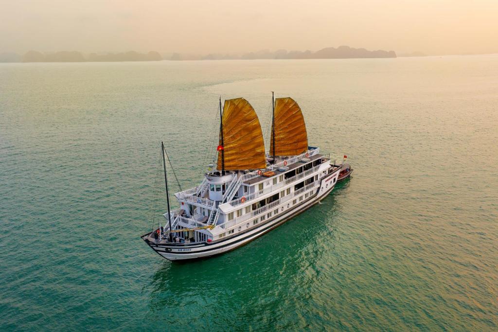 Traditional Vietnamese junk boat with golden sails on calm water near Ha Long Bay