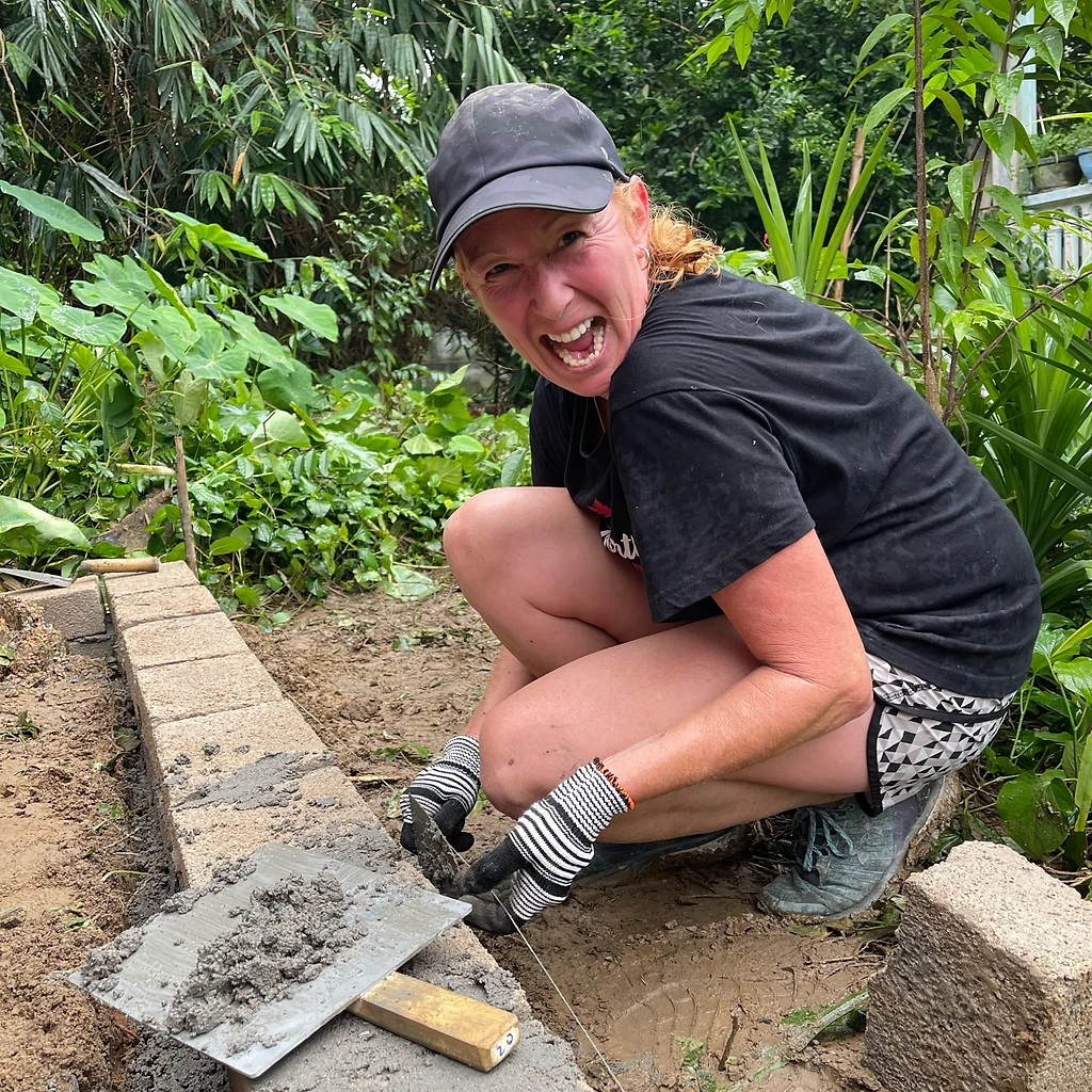 Smiling volunteer mortaring a block wall