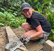 Smiling volunteer mortaring a block wall