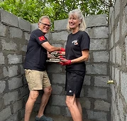 Two volunteers applying mortar to the blocks
