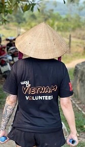 Volunteer in conical hat walking with equipment