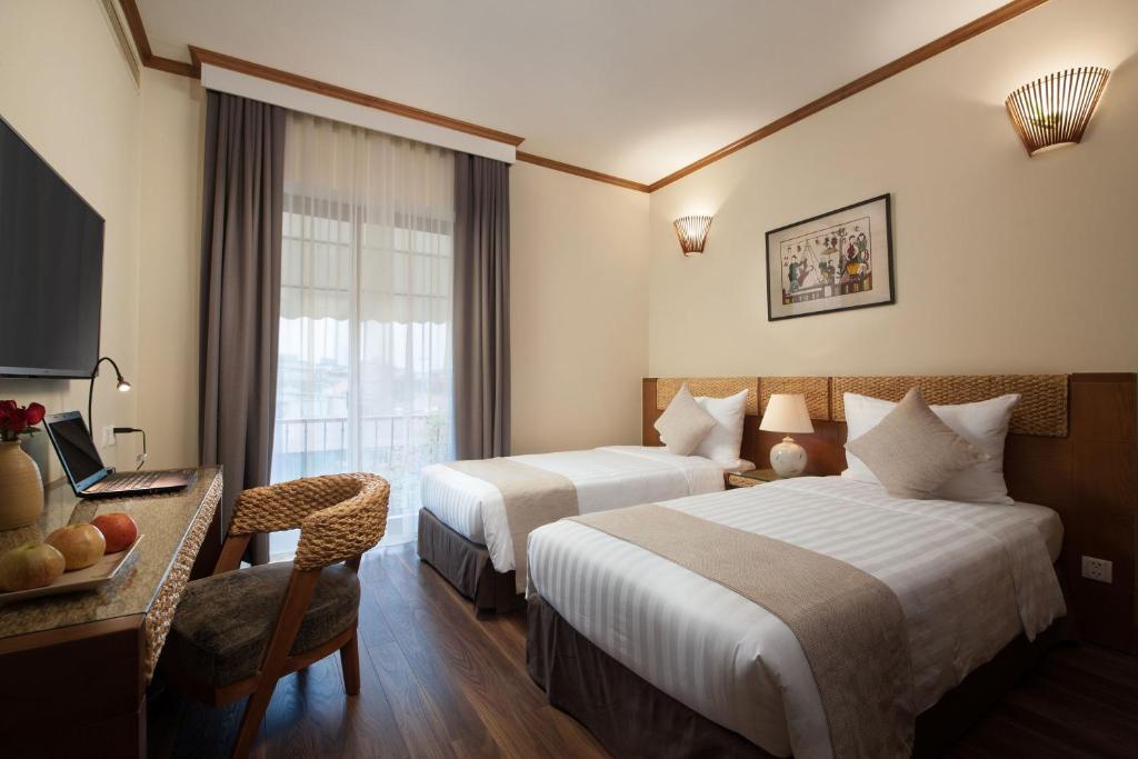 Boutique hotel room with twin beds, rattan headboard and warm wall sconces