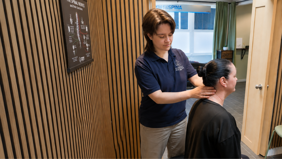 Chiropractor performing a gentle neck adjustment at Synergy Body & Spine Clinic