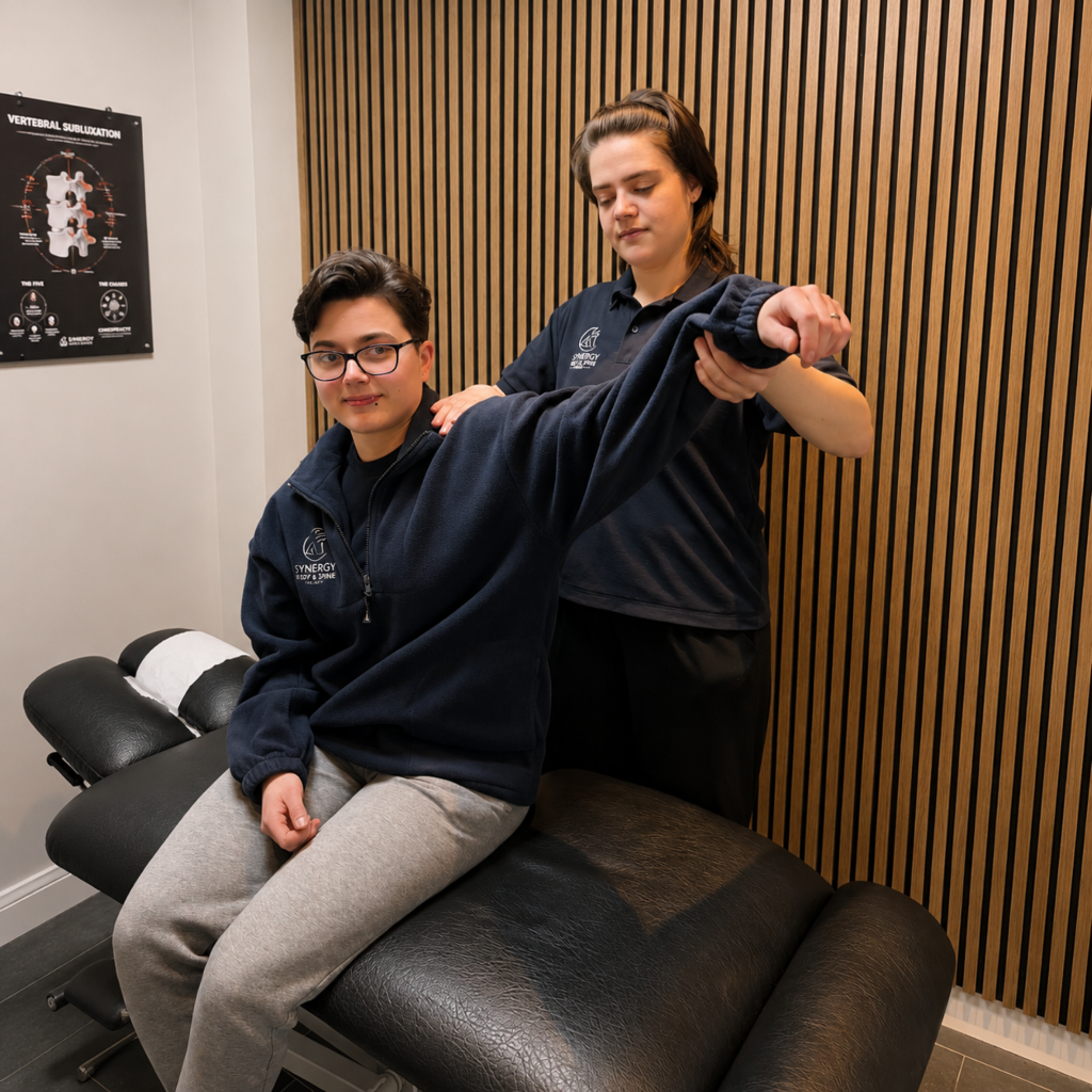Chiropractor assessing a patient's shoulder and rotator cuff at Synergy Body & Spine Clinic