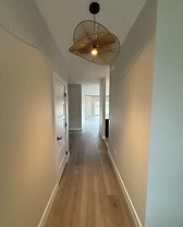 Interior hallway with a woven pendant light leading toward an open living area