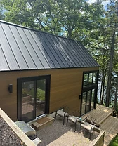 Exterior of a small secondary suite nestled among trees with a gravel patio