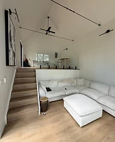 Open-concept living room with a vaulted ceiling and glass stair railing