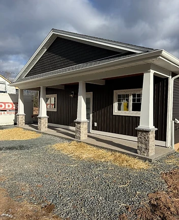 Newly built single-story home with dark siding and a full-length covered porch