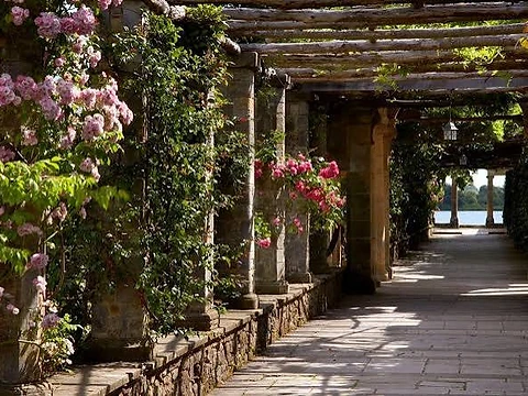 Flower-covered stone pergola walkway leading towards the lake at Hever Castle