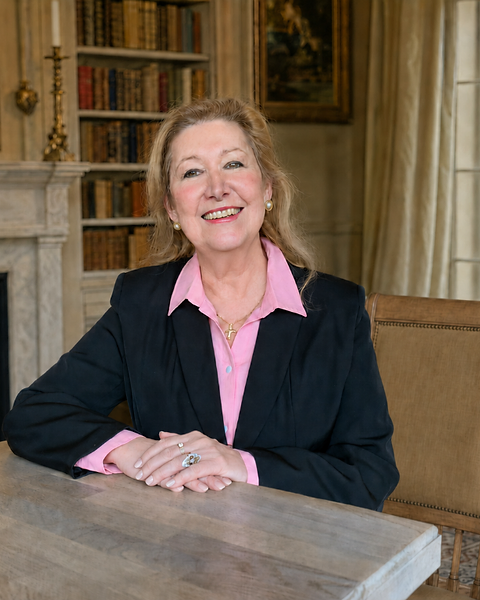 Anne Corbin seated in a warm country-house writing room