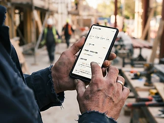 現場でスマホに表示されたまるふ工事隊のマイページを閲覧する職人の手元
