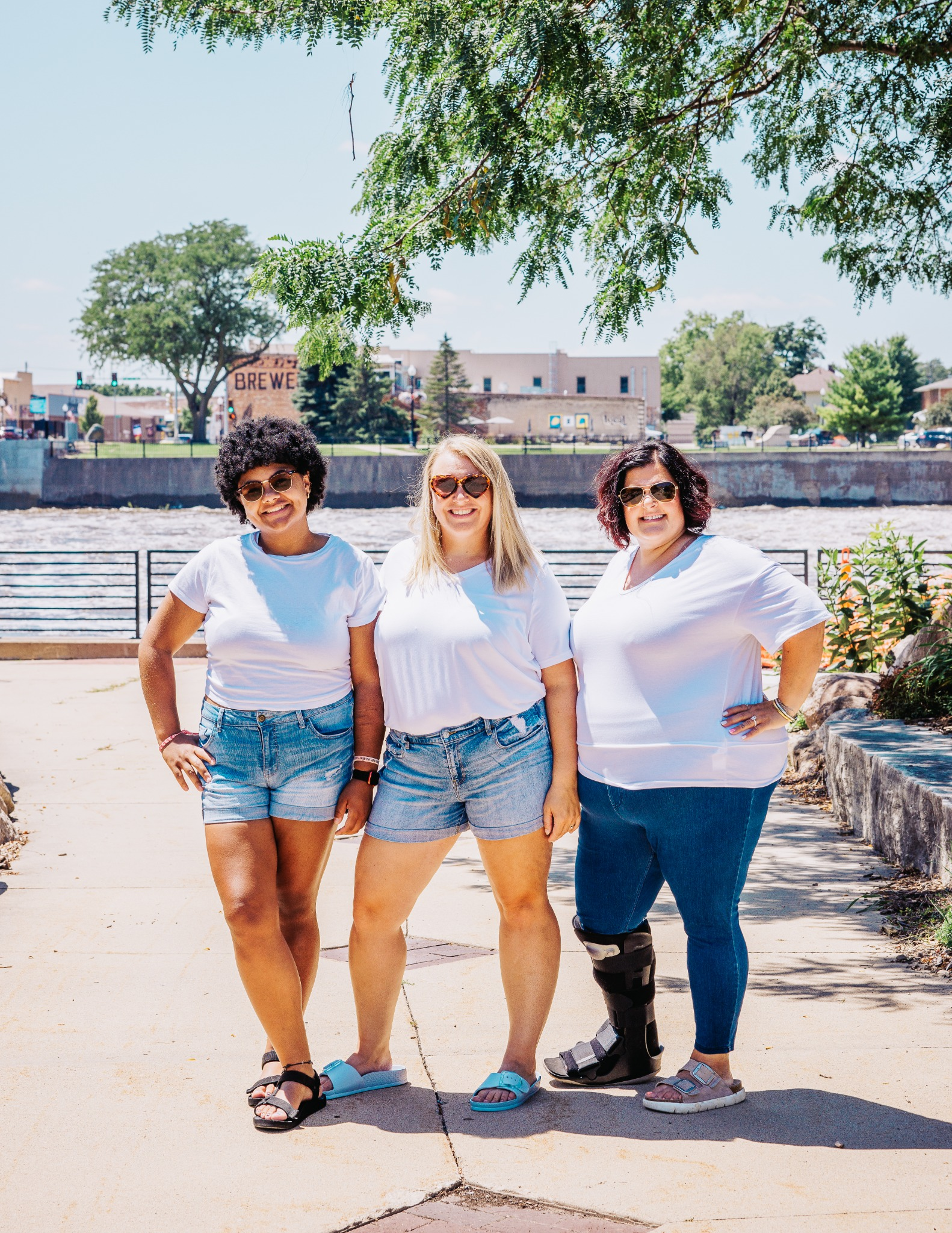The three women of Two Chicks Fluff and Fold standing together outdoors by the river
