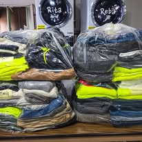 Bags of folded commercial laundry ready for return beside Two Chicks washing machines