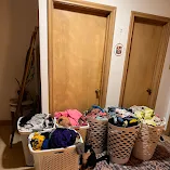 Krista's laundry before Two Chicks service — six baskets of loose, overflowing laundry filling a hallway