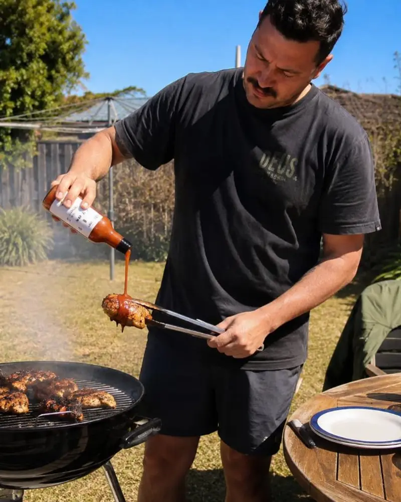 Pouring STOKE peri-peri sauce on chicken at a braai