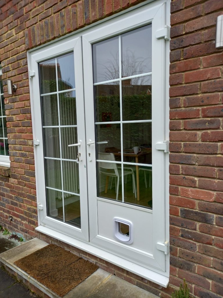 Cat flap fitted in the lower panel of a white uPVC French door