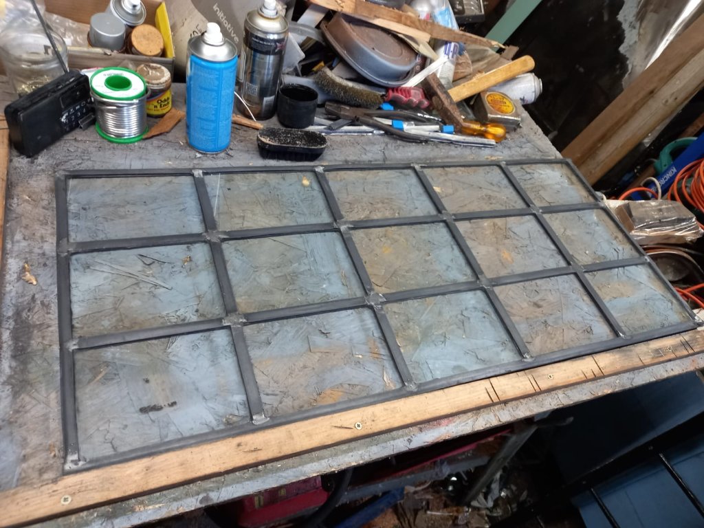 Repaired lead light panel resting on a workshop bench