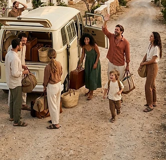 Gruppe von Freunden und Familie packt Gepäck aus dem Bus an einem Ferienhaus am Meer aus