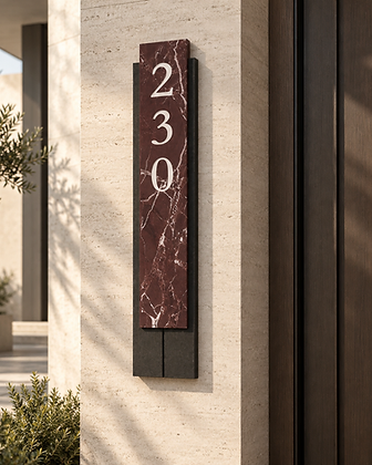 Brushed brass house number plaque with warm backlight mounted on a textured stone wall