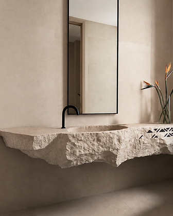 Freestanding stone sink pedestal in light travertine with a geometric star-shaped lattice cutout and brushed metal fixtures