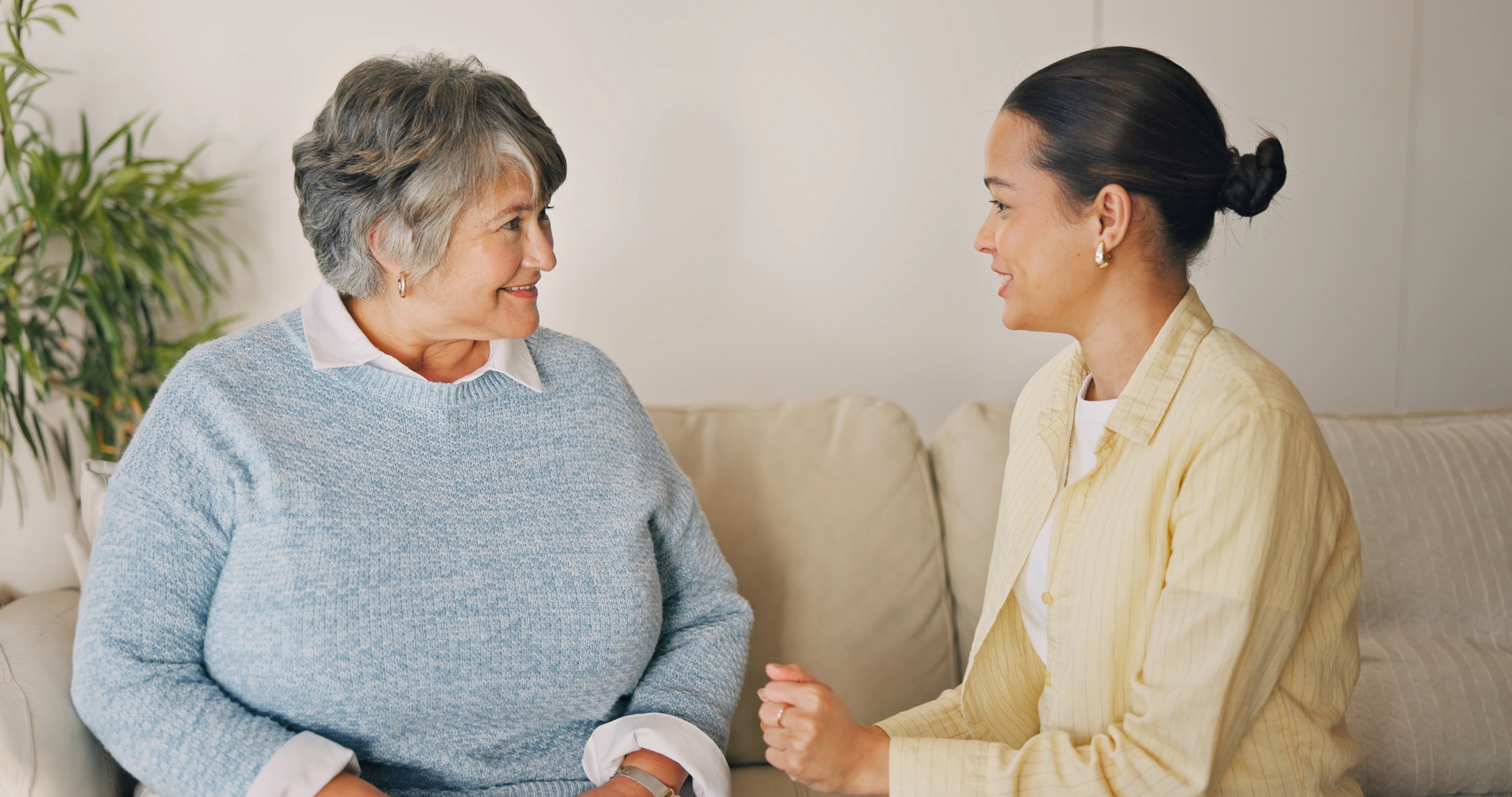 A SureWork caregiver sitting and talking with a senior client at home