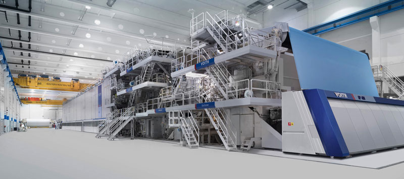 Expansive modern paper mill housing a VOITH paper machine with blue accents and a yellow overhead crane