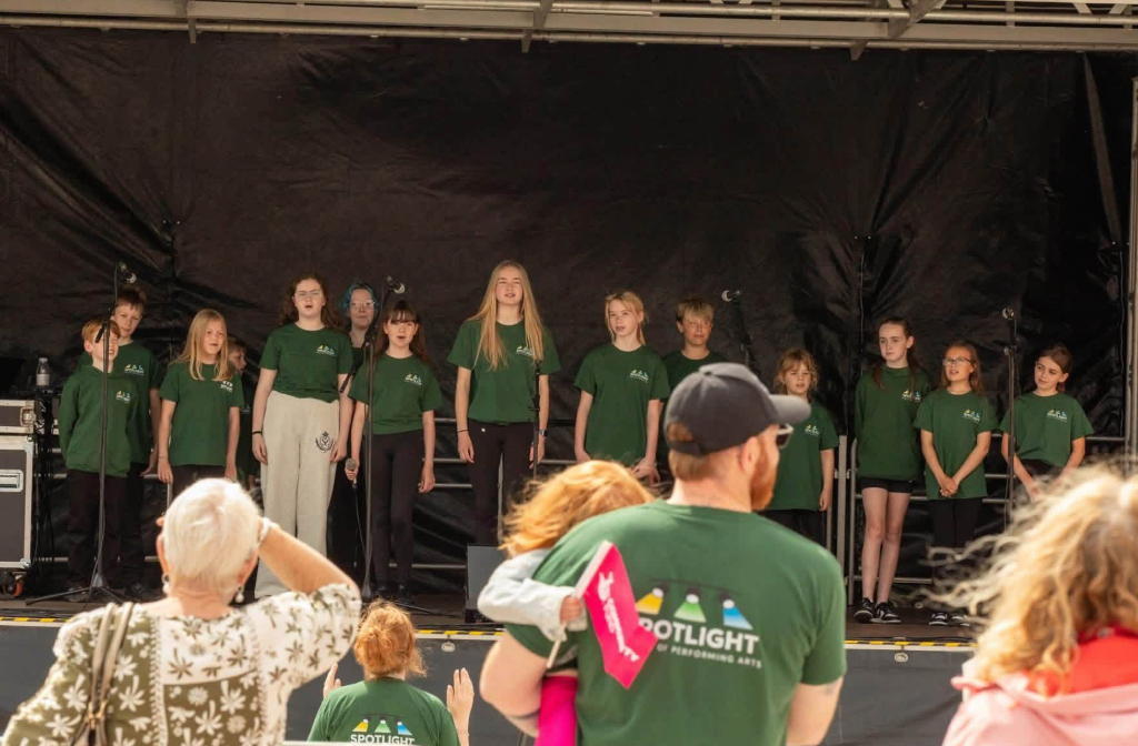 Students performing on stage in Spotlight hoodies