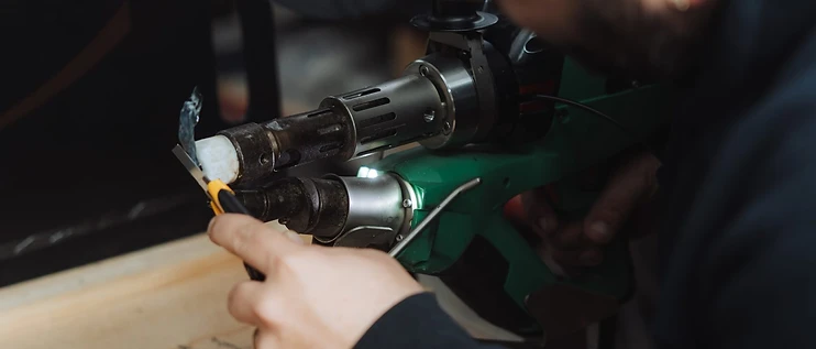 B&M Plastics welder using a handheld welding tool on a plastic component on the workshop bench