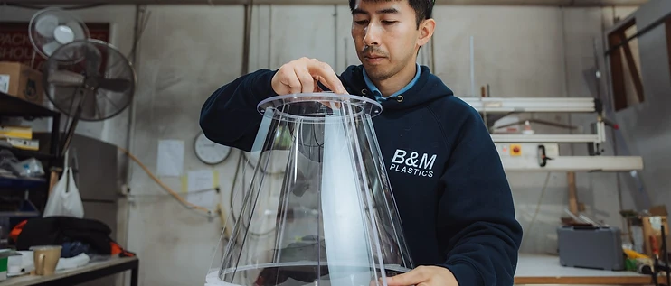 B&M Plastics technician assembling a clear conical plastic component on the workshop bench
