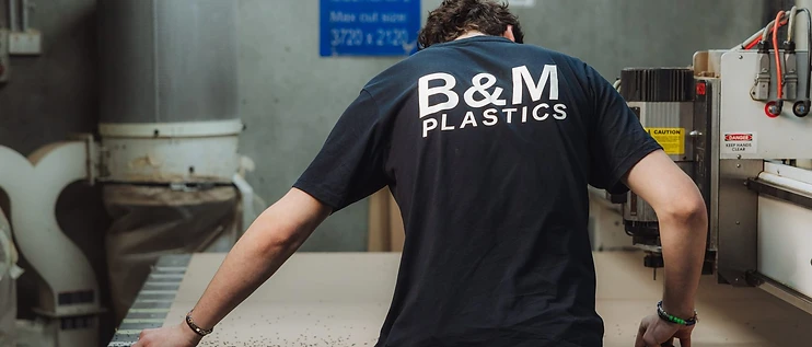 B&M Plastics operator measuring material on the MultiCam CNC router at the Yennora workshop