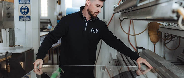 B&M Plastics technician line bending a clear acrylic sheet on the workshop bench