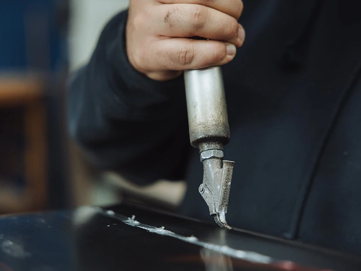 Close-up of B&M Plastics technician hot-gas welding a seam with a Leister heat welding tool