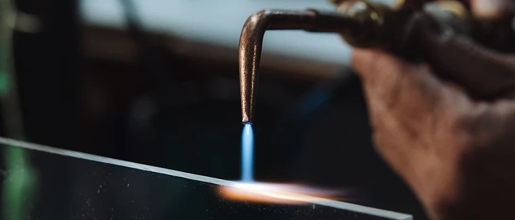 Flame-polishing the edge of a clear plastic sheet with a handheld torch at B&M Plastics