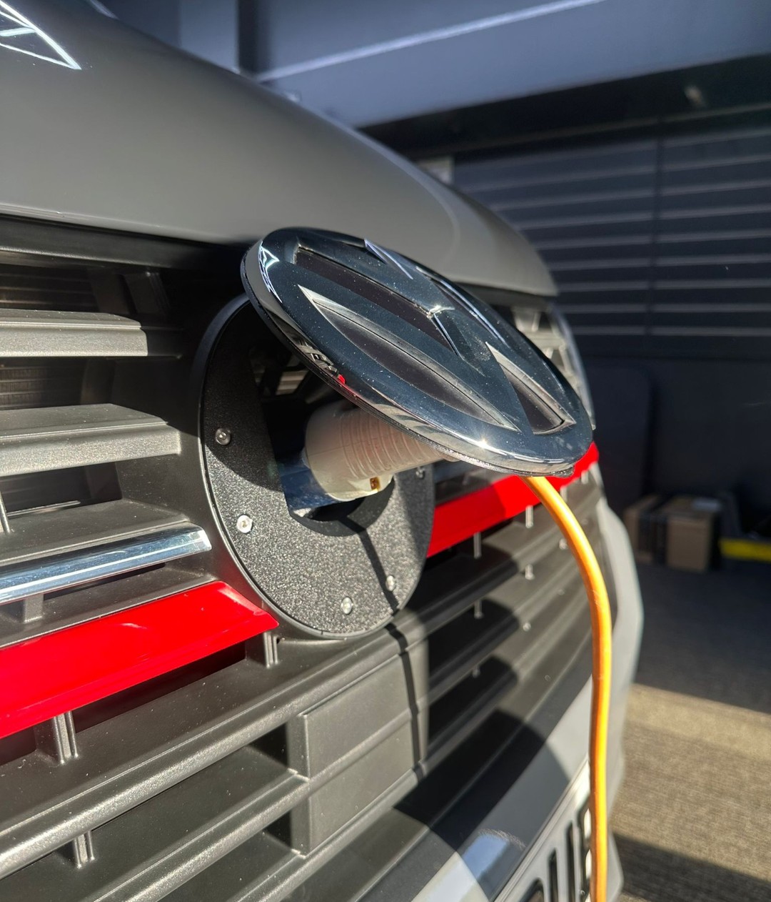Grey VW van charging port with orange cable