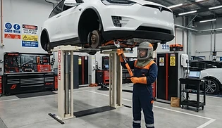EV service bay with an electric vehicle and a technician in full arc-flash PPE
