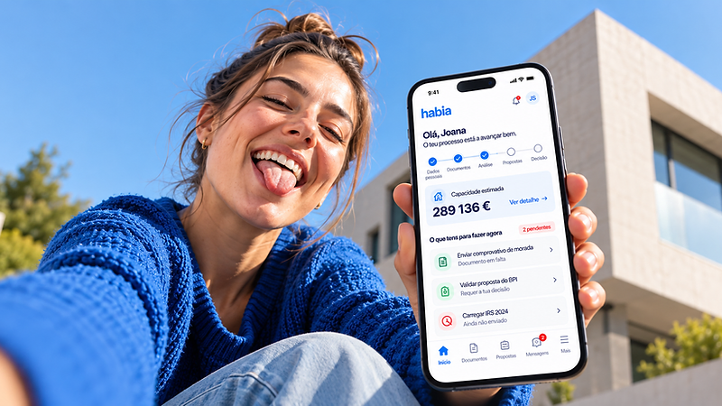 Mulher a sorrir ao ar livre, de língua de fora, a mostrar o telemóvel com a app Habia e o estado do seu processo de crédito.