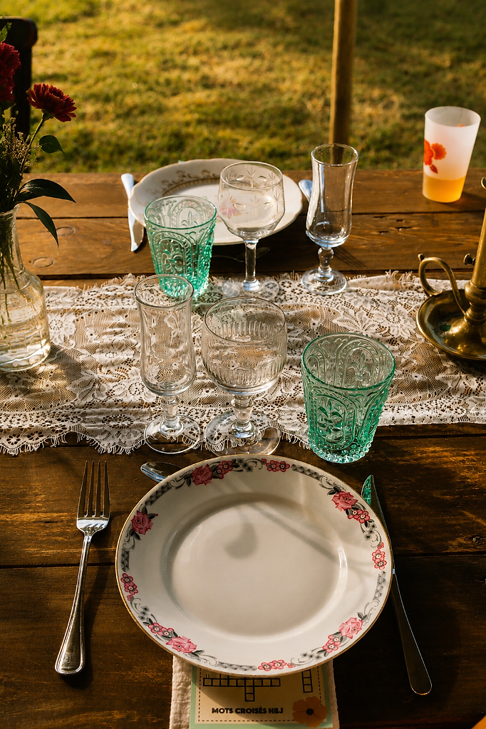Table de réception avec vaisselle vintage, dentelle et verres colorés
