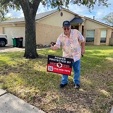 Excited homeowner dancing next to Gen Pro Generators power protected sign at Houston Texas ranch home
