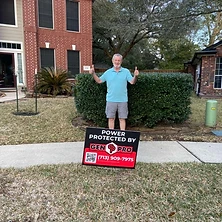 Man giving double thumbs up by A&A GenPro power protected sign at Houston brick home
