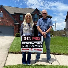 Couple standing with A&A GenPro installation sign in front of Houston Texas brick home