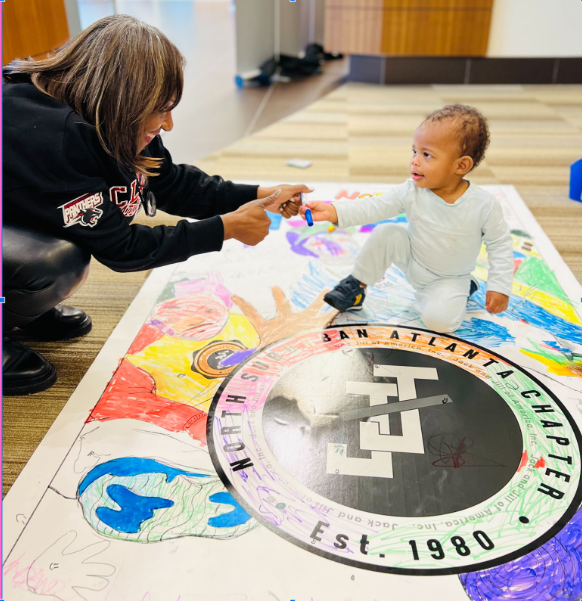 An NSAC mother and child coloring together on the chapter's commemorative banner