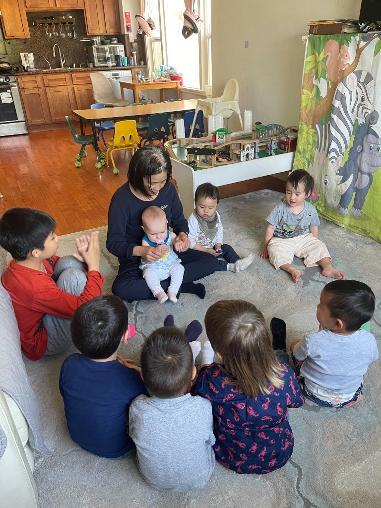Children gathered around a teacher on the playroom rug