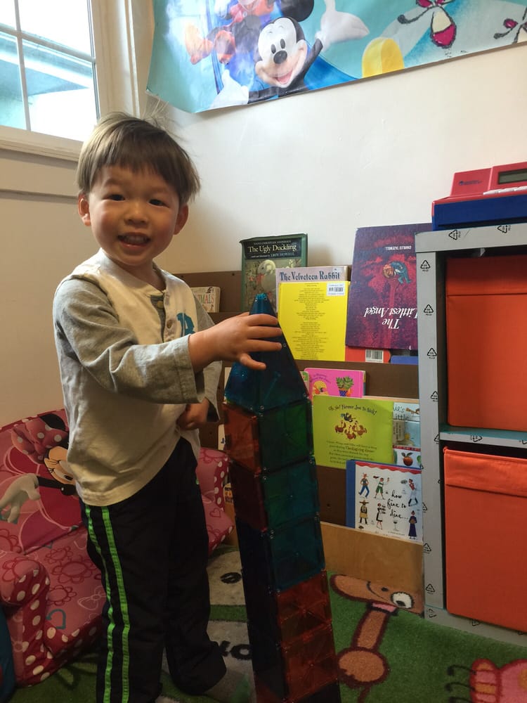 A boy smiling with a tower of magnetic tiles