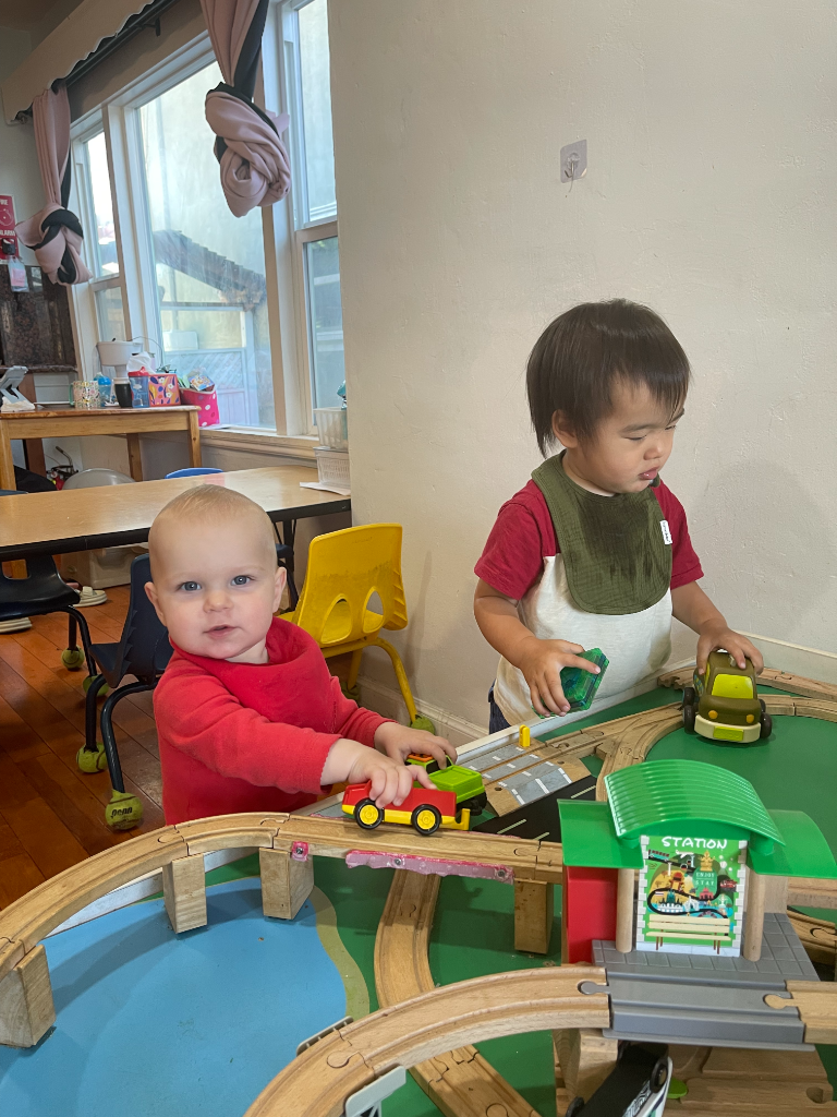Two children playing with a wooden train set