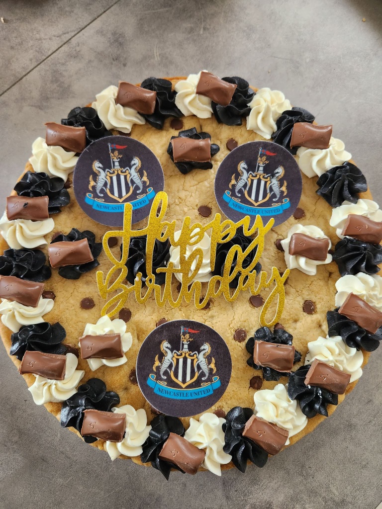 Giant chocolate-chip birthday cookie decorated with a Newcastle United crest and Happy Birthday topper