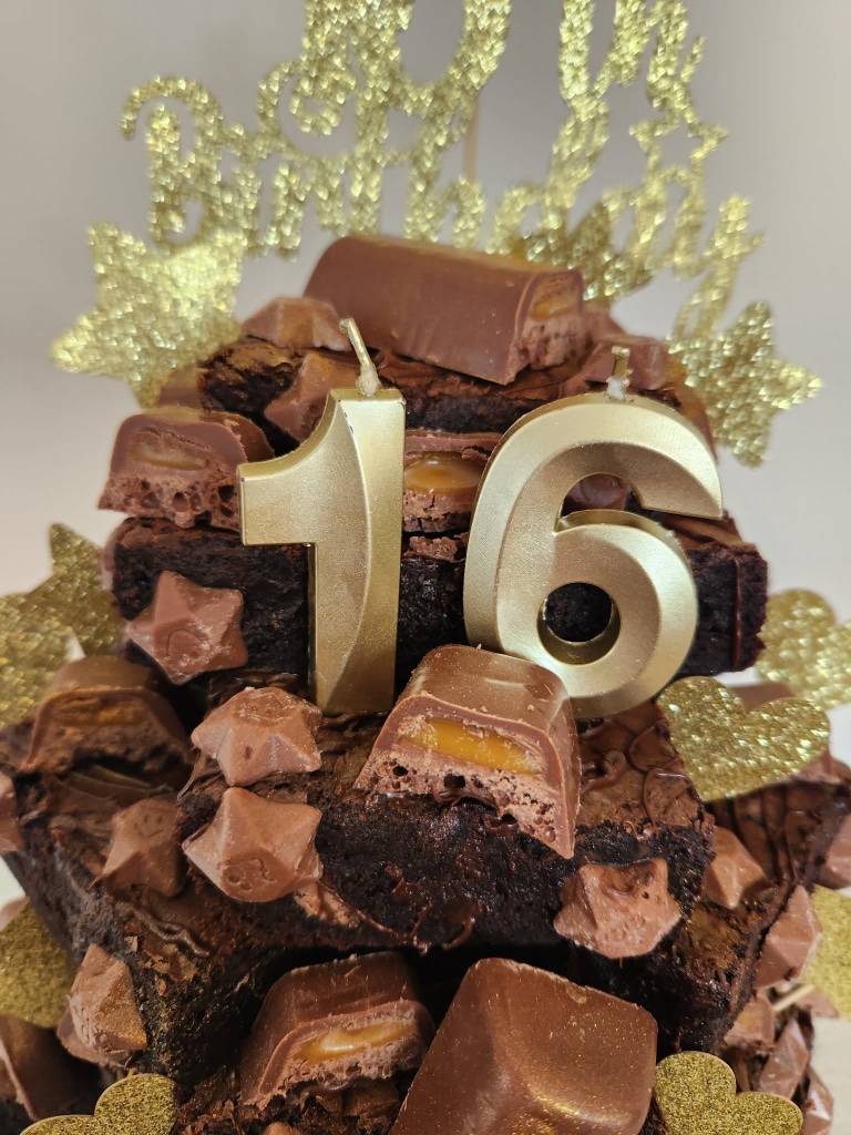 Tiered birthday brownie stack decorated with gold number candles and a Happy Birthday topper