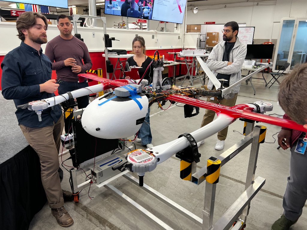 A technical team examining a large uncrewed aircraft in an engineering workspace.