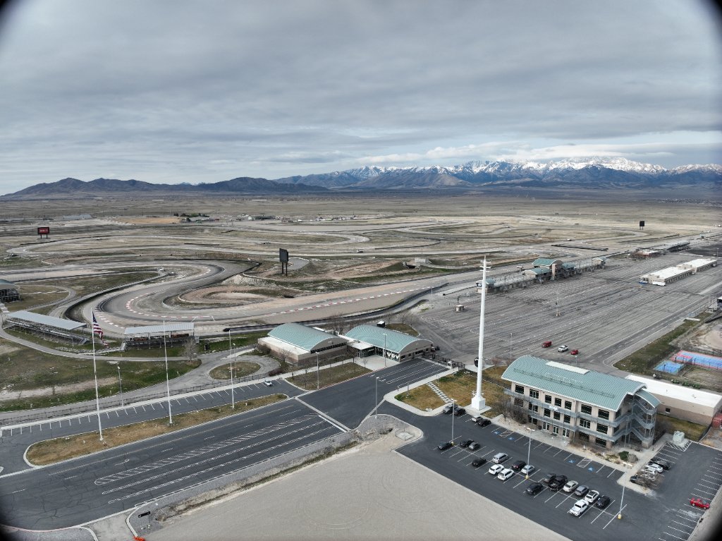 Wide aerial documentation of a large motorsports and event facility set within a mountain landscape.